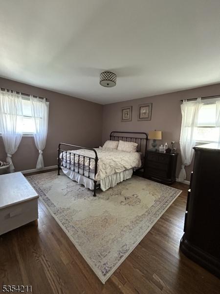 bedroom with dark wood-style flooring and multiple windows