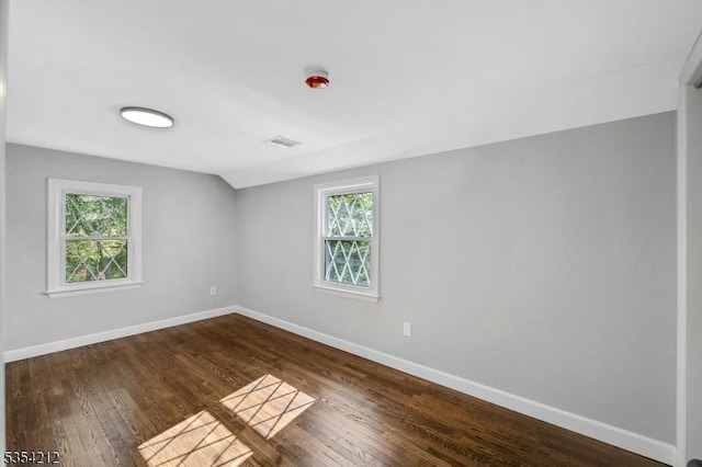 spare room featuring a healthy amount of sunlight, baseboards, and dark wood-type flooring