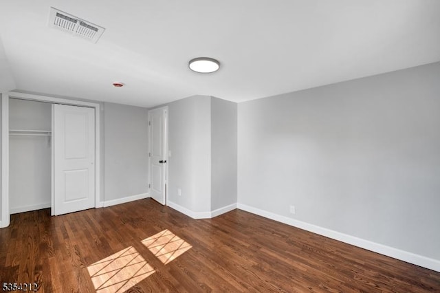 unfurnished bedroom featuring baseboards, a closet, wood finished floors, and visible vents