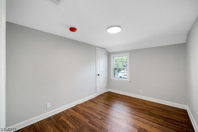 unfurnished room featuring baseboards and dark wood-type flooring
