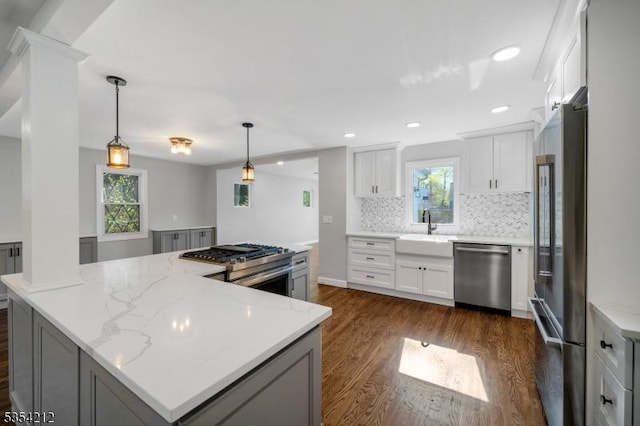 kitchen featuring decorative backsplash, dark wood-style flooring, a large island, appliances with stainless steel finishes, and a sink