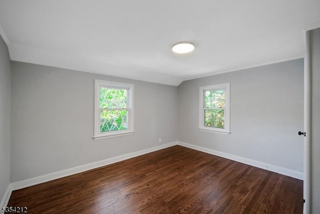 unfurnished room with baseboards and dark wood-type flooring