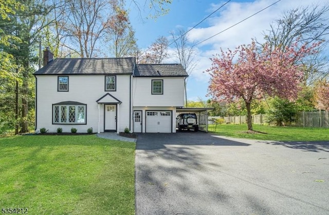 view of front of house with aphalt driveway, fence, a front yard, a chimney, and a carport
