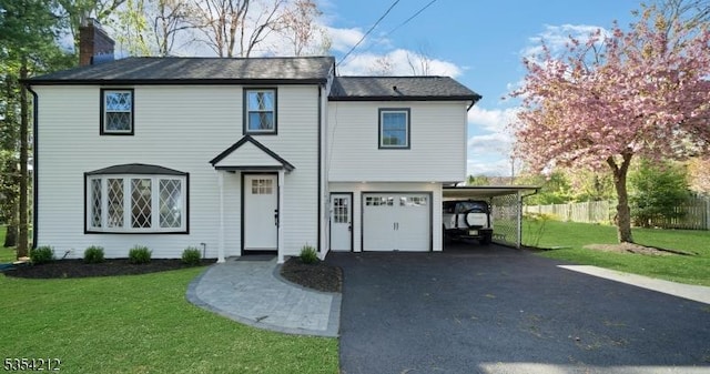 traditional-style house with a front yard, a chimney, an attached garage, driveway, and a carport