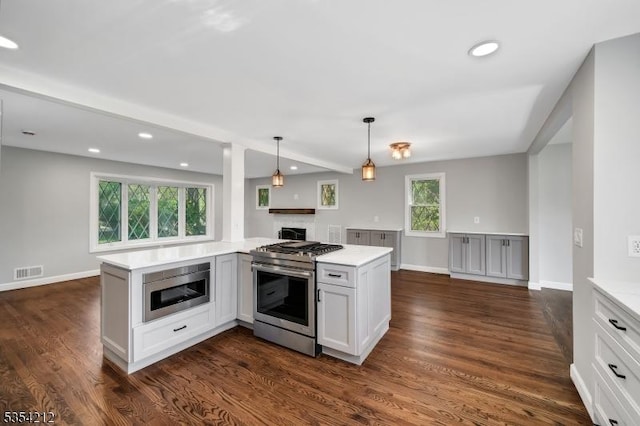 kitchen featuring dark wood-style flooring, visible vents, appliances with stainless steel finishes, a fireplace, and recessed lighting