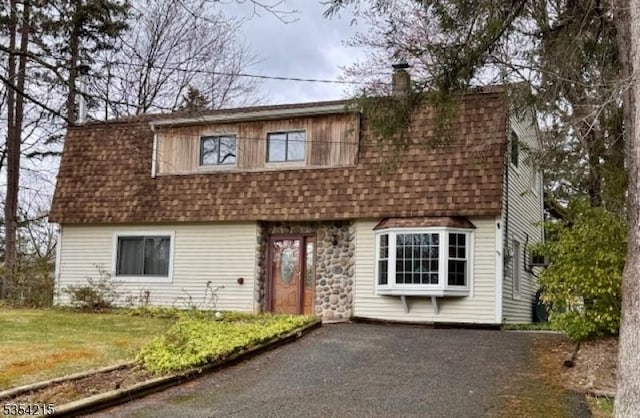view of front of house featuring roof with shingles, a front yard, and a chimney