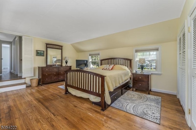 bedroom featuring baseboards, wood finished floors, and lofted ceiling