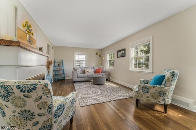 living area with baseboards, wood finished floors, and visible vents