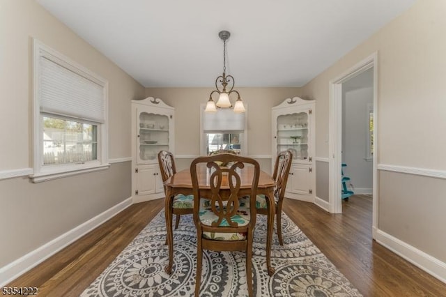 dining room featuring dark wood-style flooring, baseboards, and an inviting chandelier