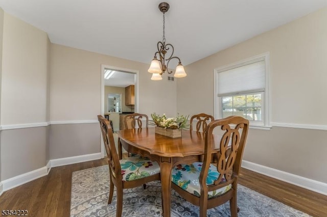 dining area with baseboards, wood finished floors, and a notable chandelier