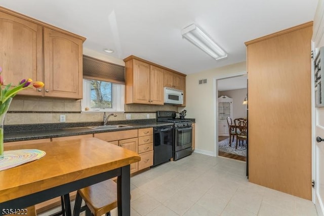 kitchen featuring visible vents, a sink, black appliances, and tasteful backsplash