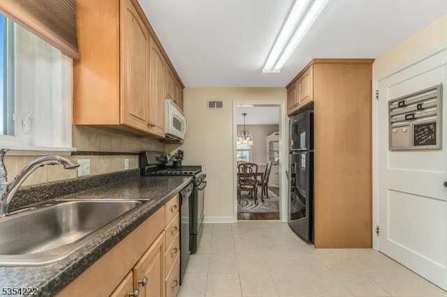 kitchen featuring a sink, dark countertops, black appliances, and visible vents