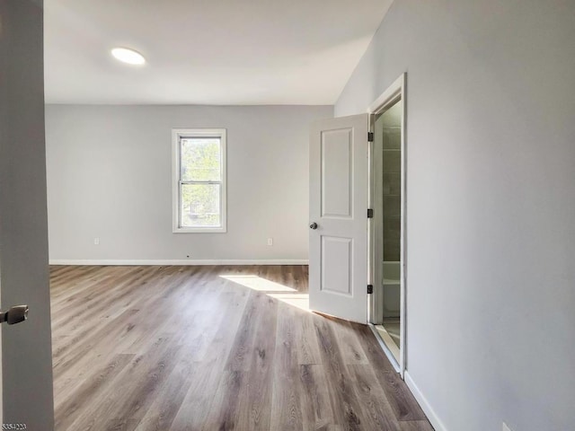 empty room with baseboards, wood finished floors, and lofted ceiling