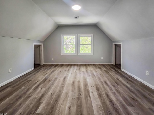 additional living space featuring baseboards, visible vents, wood finished floors, and lofted ceiling