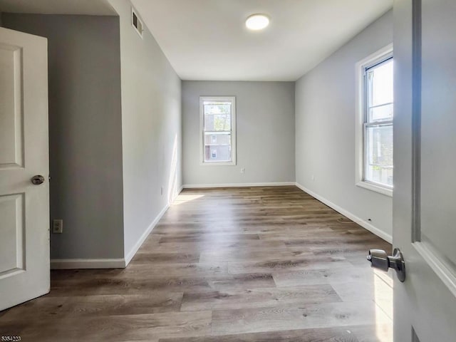 spare room with baseboards, wood finished floors, and visible vents