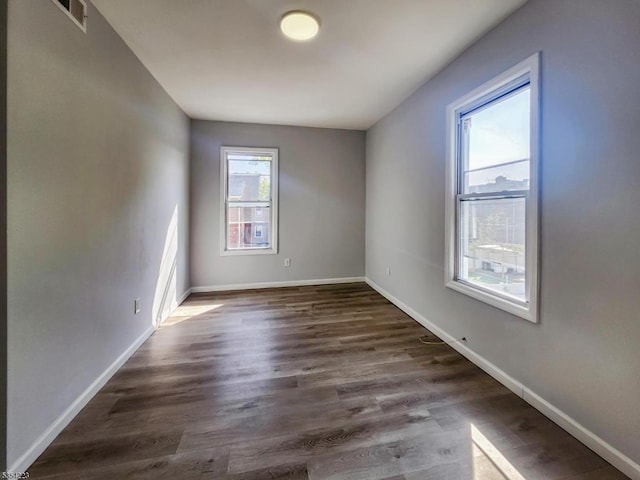 unfurnished room featuring baseboards, visible vents, and dark wood-type flooring