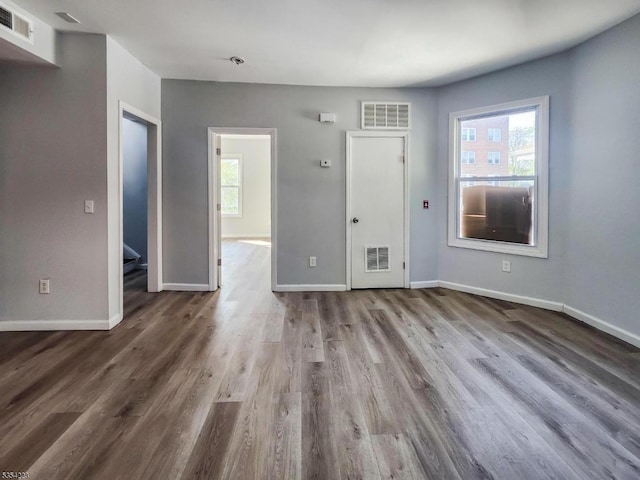 unfurnished living room featuring baseboards, visible vents, and wood finished floors