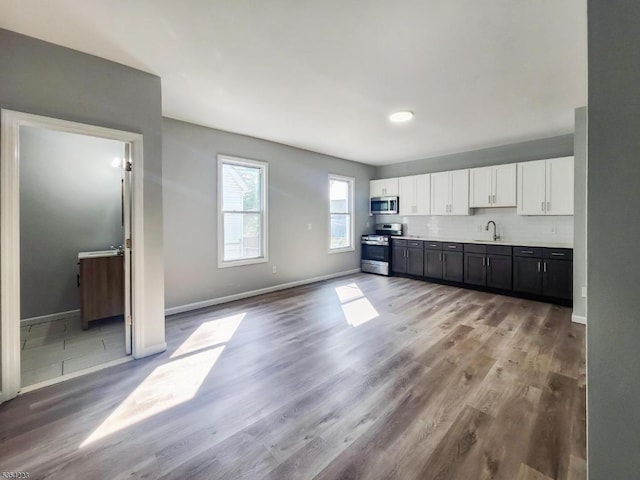 kitchen with light wood-type flooring, light countertops, white cabinets, a sink, and appliances with stainless steel finishes