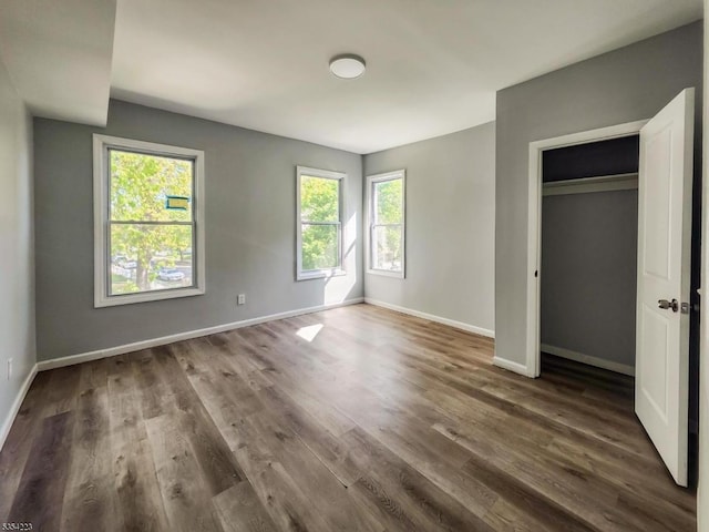 unfurnished bedroom featuring baseboards, dark wood-style floors, and multiple windows