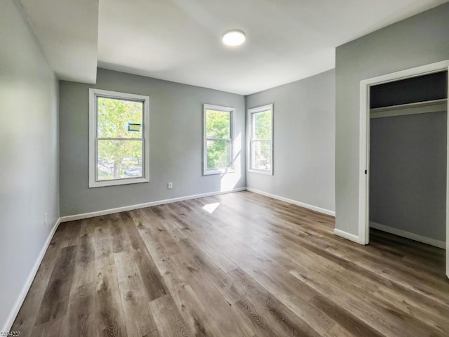 unfurnished bedroom featuring baseboards, a closet, and wood finished floors