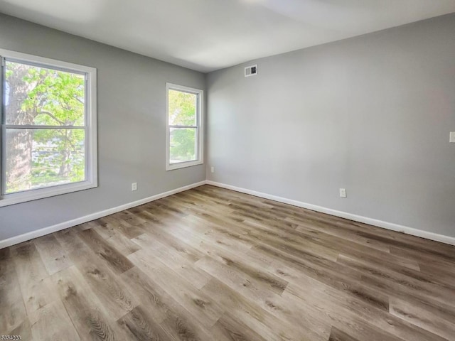 spare room with baseboards, wood finished floors, and visible vents