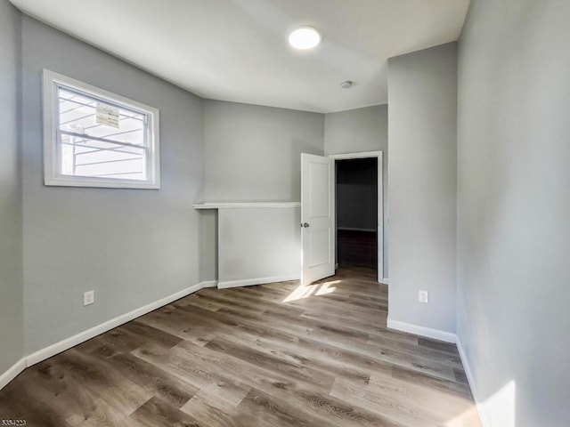 spare room featuring baseboards and wood finished floors