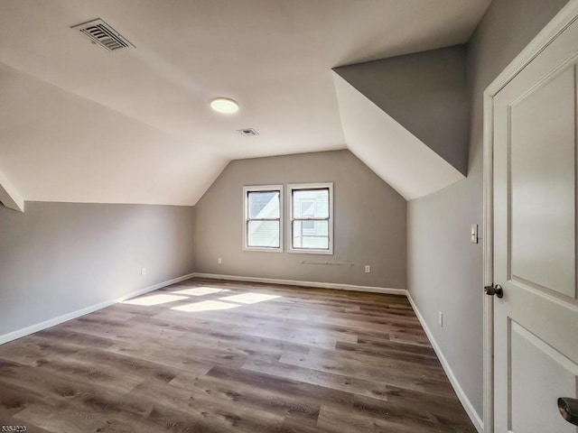 bonus room featuring baseboards, lofted ceiling, wood finished floors, and visible vents