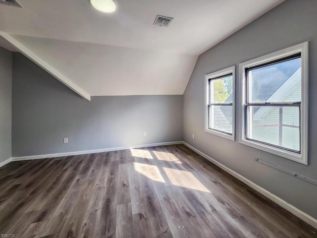 bonus room featuring baseboards, visible vents, vaulted ceiling, and dark wood-type flooring
