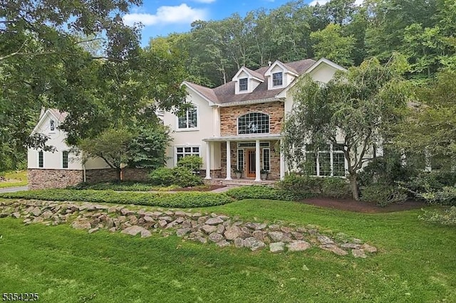 view of front of house featuring brick siding, stucco siding, stone siding, and a front yard