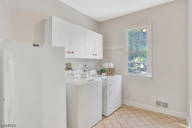 clothes washing area featuring visible vents, washer and dryer, baseboards, cabinet space, and light tile patterned floors