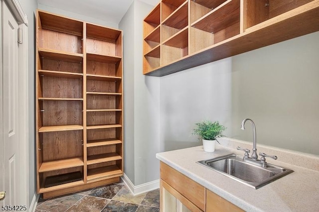 interior space featuring baseboards, a sink, and stone finish floor