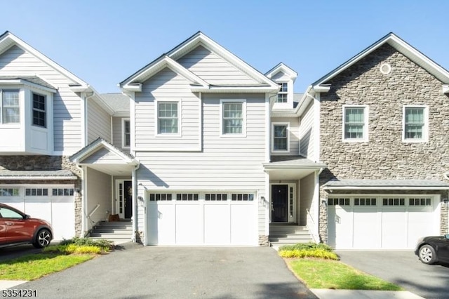 multi unit property with a garage, aphalt driveway, and stone siding