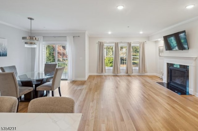 living area featuring light wood-style floors, a fireplace with flush hearth, baseboards, and crown molding
