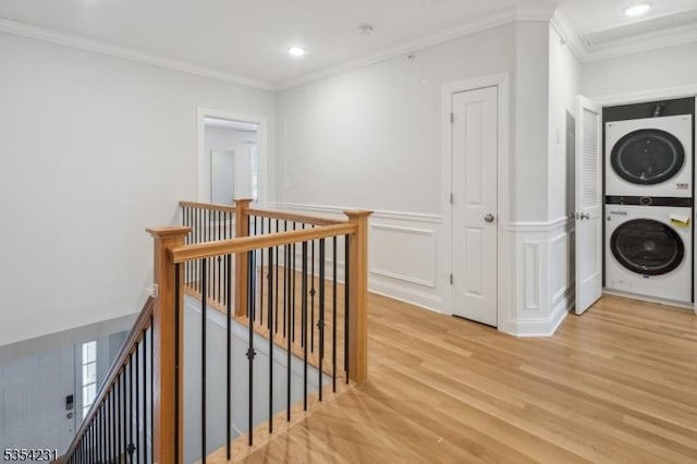 hallway with ornamental molding, recessed lighting, light wood-style flooring, stacked washer / drying machine, and an upstairs landing