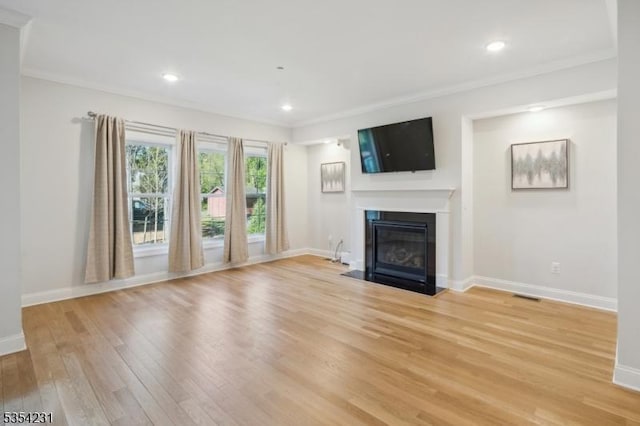 unfurnished living room with crown molding, light wood-style floors, recessed lighting, baseboards, and a fireplace with flush hearth