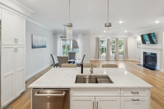 kitchen with stainless steel dishwasher, open floor plan, light wood-style floors, and crown molding