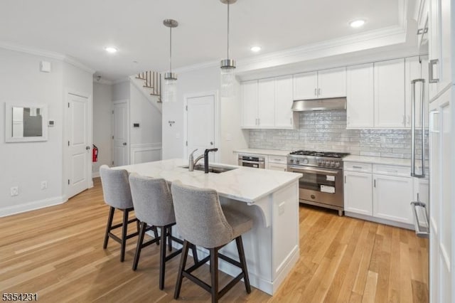 kitchen with crown molding, high end stainless steel range, a sink, a kitchen breakfast bar, and backsplash