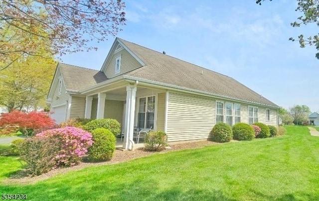 view of home's exterior featuring an attached garage, a yard, and a porch