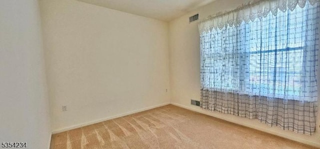 unfurnished room featuring visible vents, carpet, and baseboards