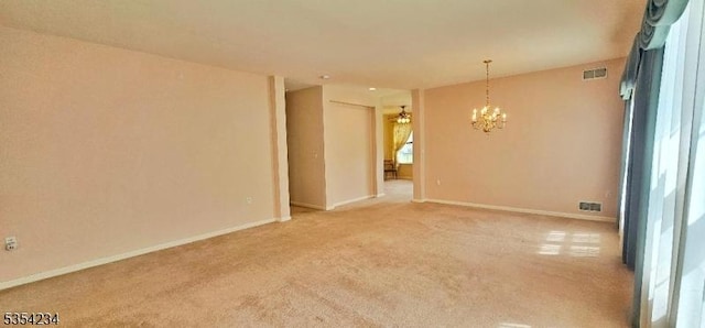 spare room featuring baseboards, visible vents, light carpet, and a chandelier