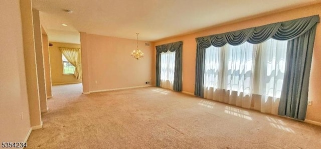 carpeted empty room with baseboards and a notable chandelier