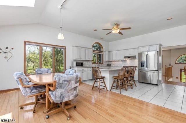 dining area featuring a ceiling fan, light wood finished floors, and lofted ceiling