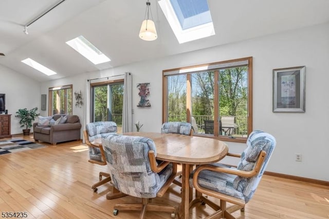 dining room with light wood-style floors, baseboards, and lofted ceiling with skylight