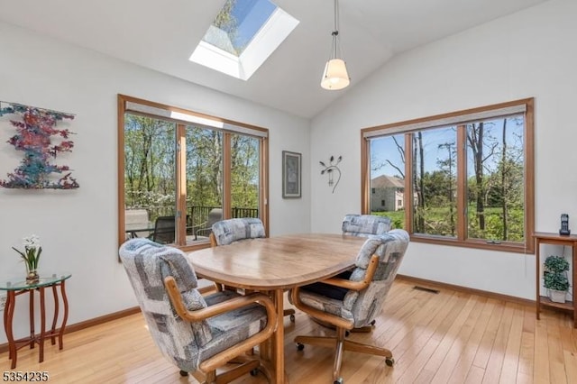 dining space with lofted ceiling with skylight, baseboards, plenty of natural light, and light wood finished floors