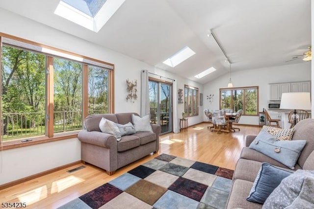 living room with lofted ceiling with skylight, light wood-style flooring, and a wealth of natural light