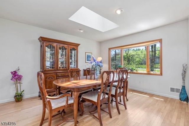 dining area with baseboards, light wood-style flooring, visible vents, and a skylight