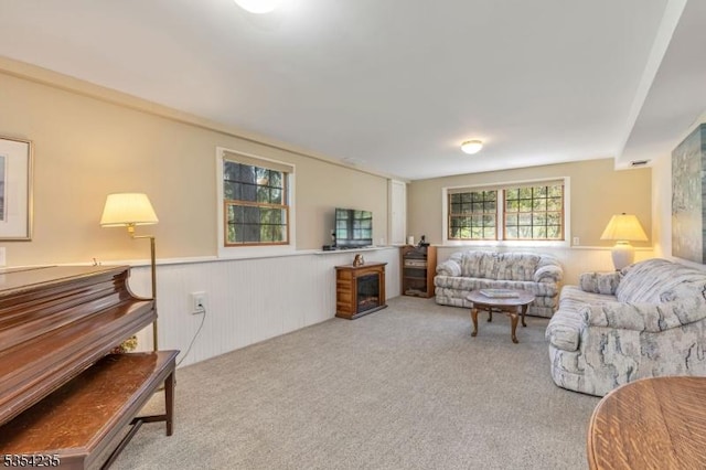 living area with carpet flooring, a wainscoted wall, and a fireplace