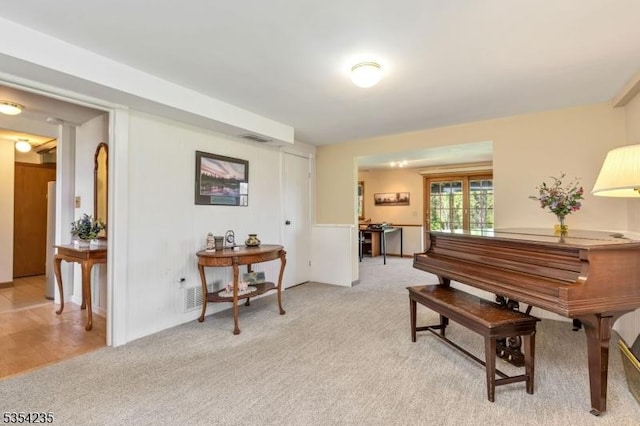 living area with visible vents and light carpet