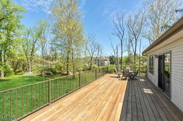 wooden terrace with outdoor dining space and a yard