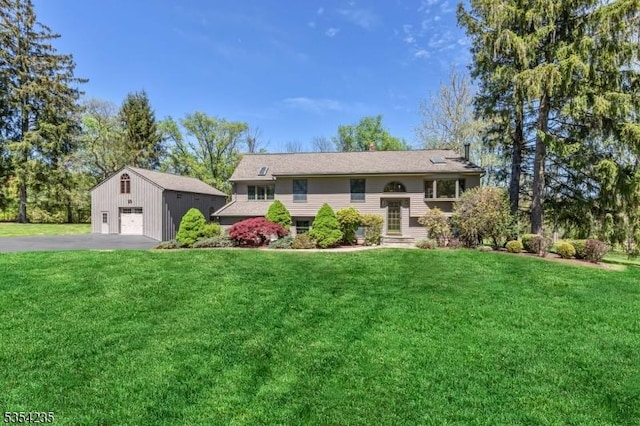 raised ranch with a detached garage, an outbuilding, driveway, and a front yard
